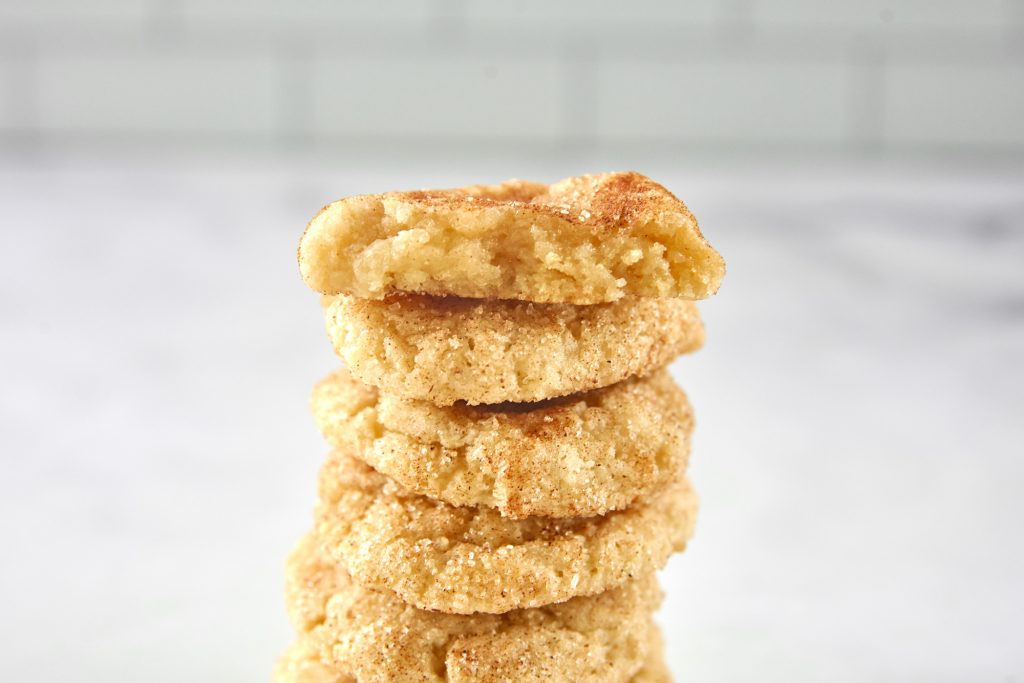 one cinnamon snickerdoodle cookie cut in half on top of a stack so you can see the inside