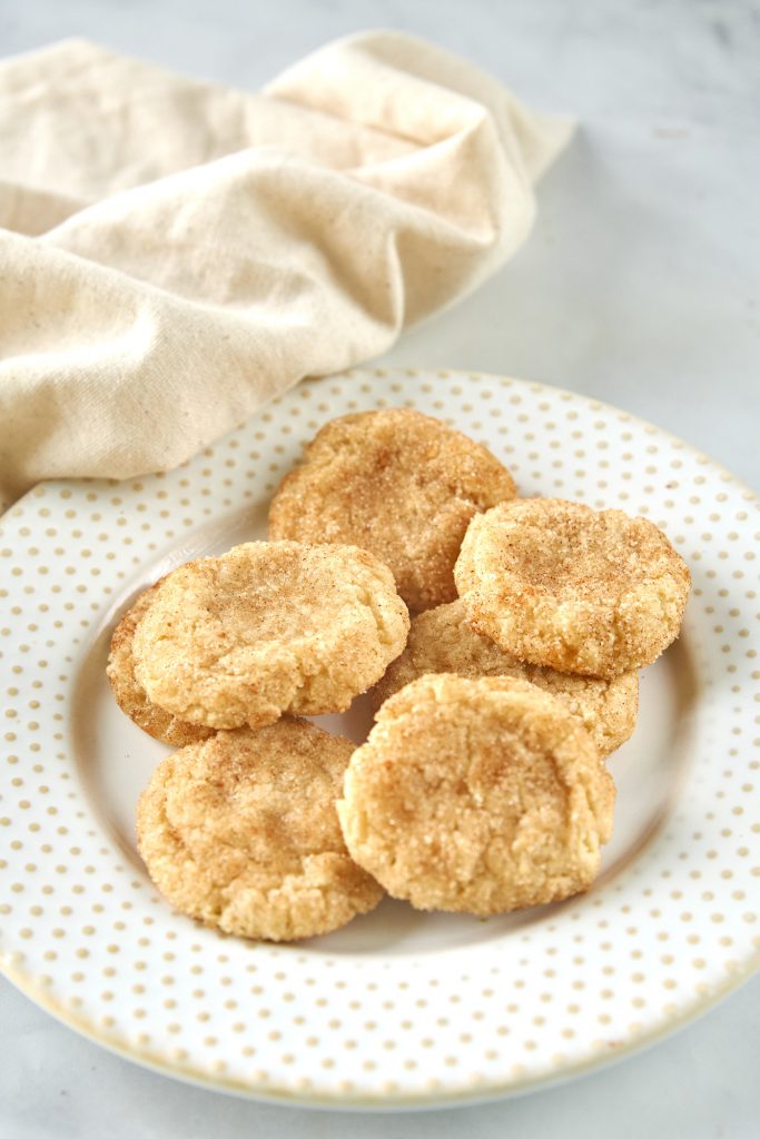 vegan snickerdoodle cookies on a plate with a dish towel
