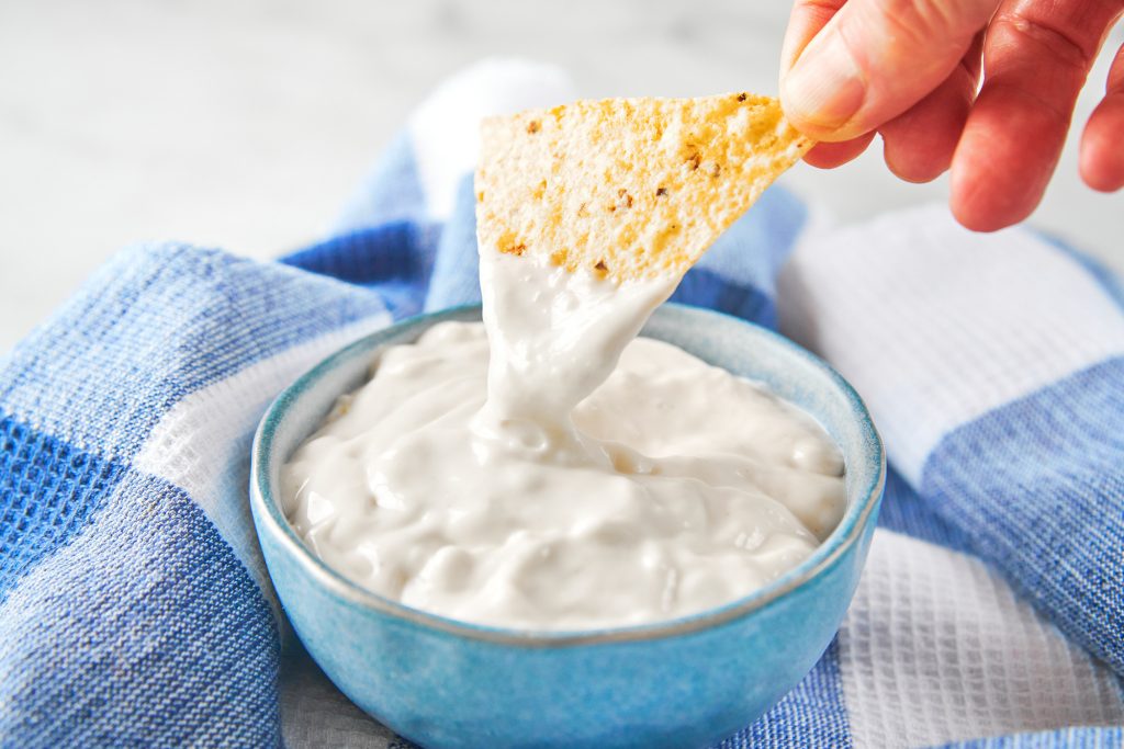 dipping a chip into vegan sour cream