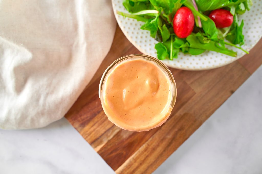 above view of vegan thousand island dressing in a jar with a salad on the side