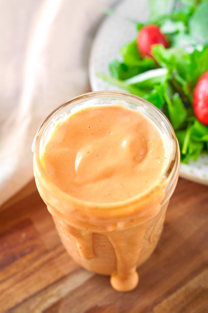 vegan thousand island dressing in a container with dressing spilling over the side