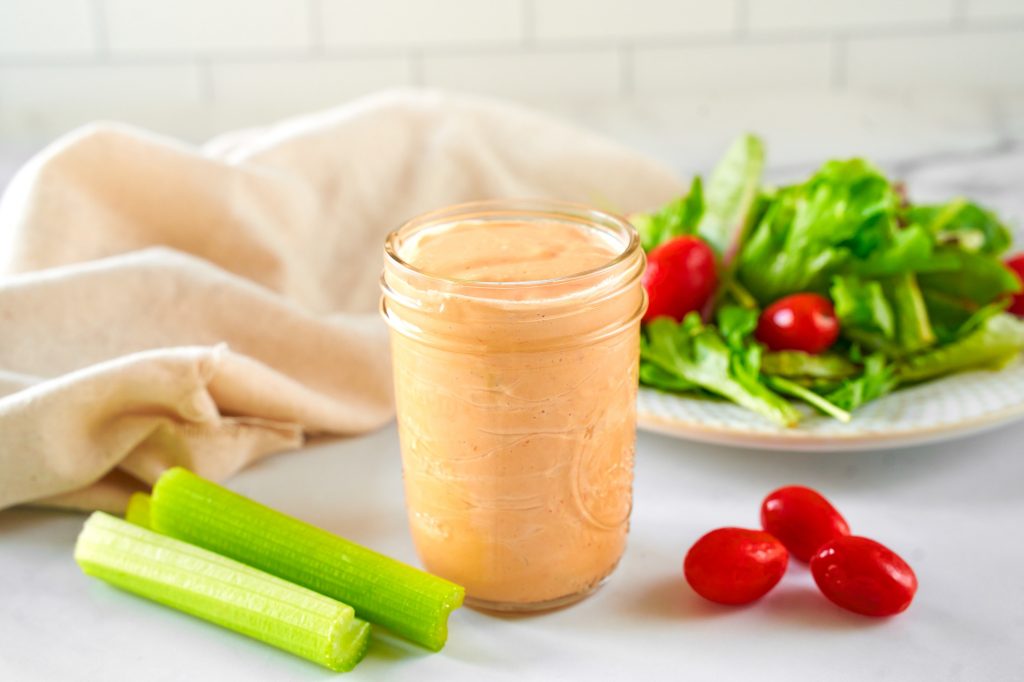 vegan thousand island dressing in a jar with a crisp salad in the background