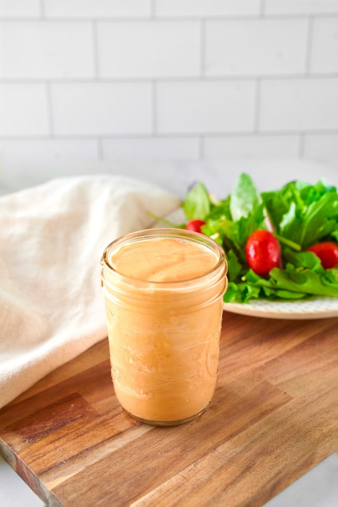 jar of vegan thousand island dressing with a salad