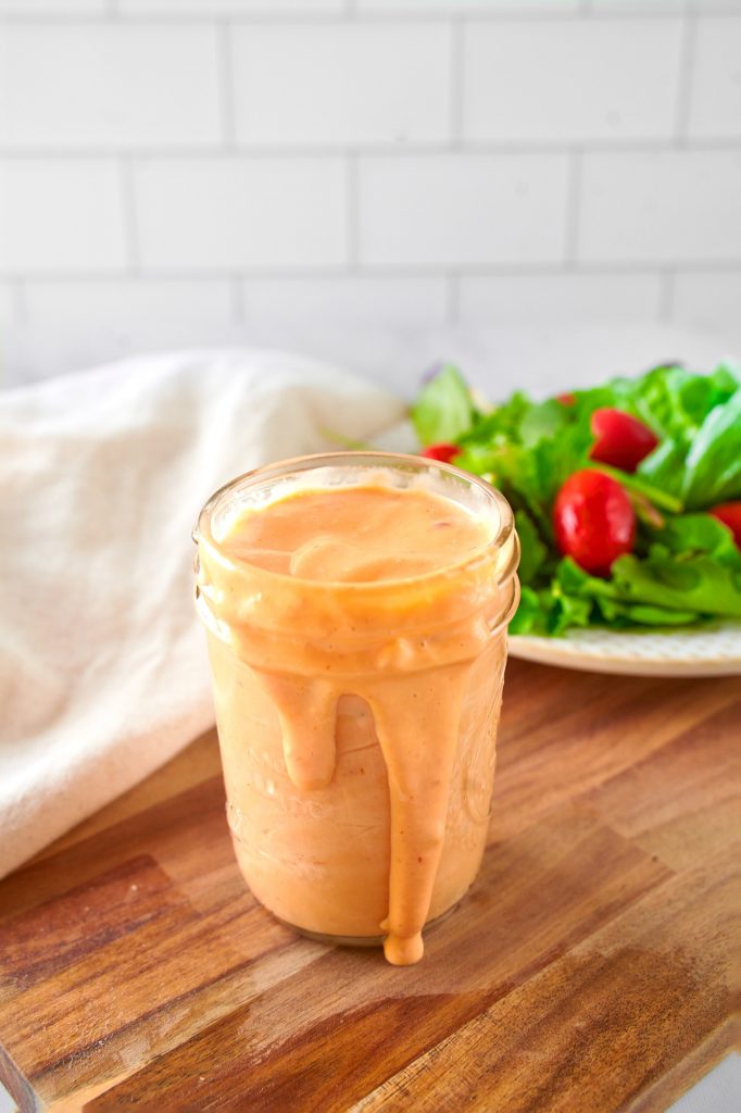 vegan thousand island dressing spilling out of a jar onto a cutting board