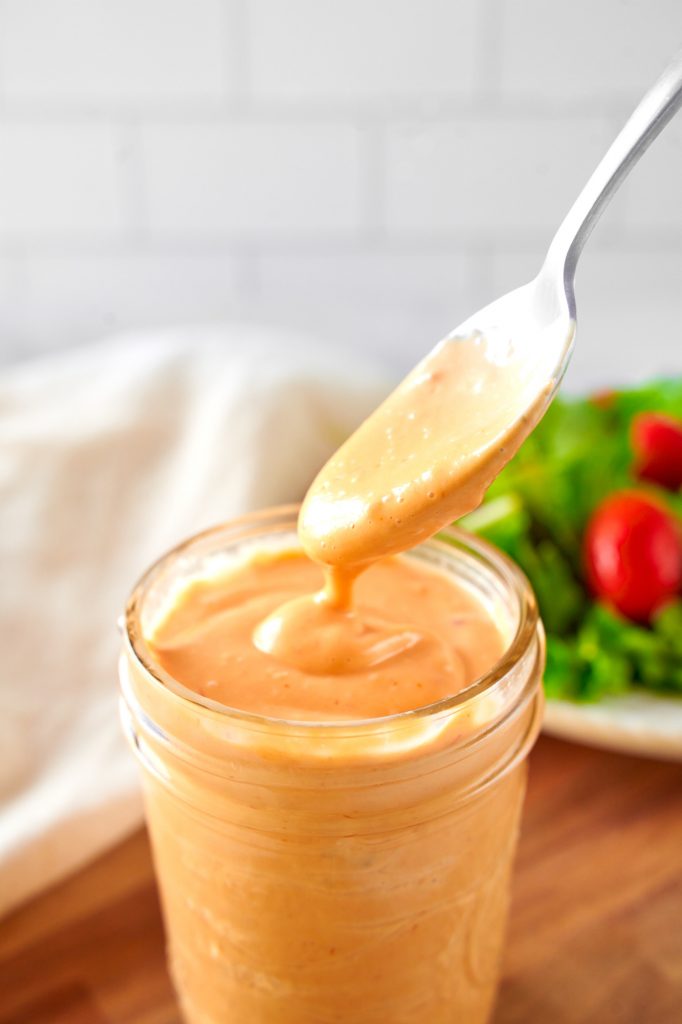 spoon picking up vegan thousand island dressing out of a jar