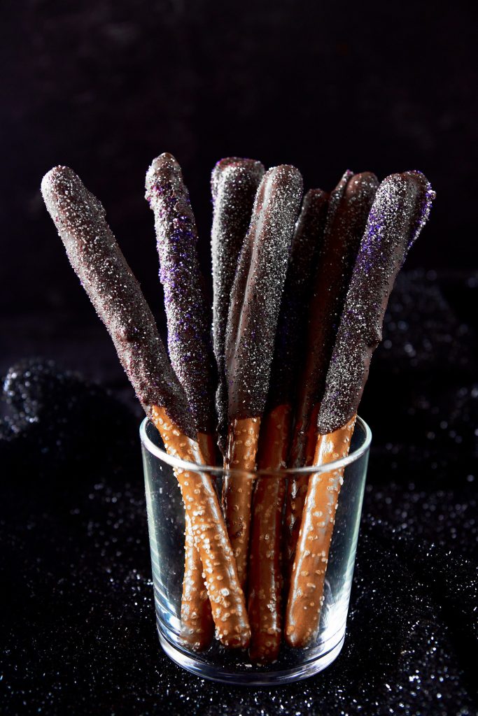 Hocus pocus halloween pretzels standing up in a glass on a black background