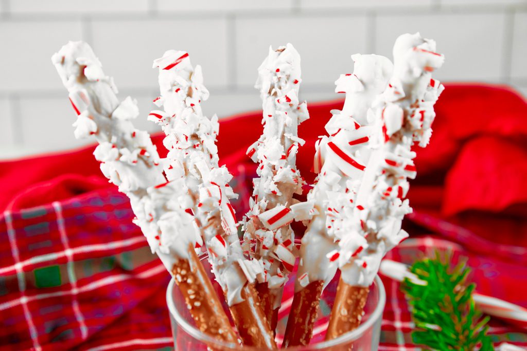 close up of white chocolate dipped pretzels rolled in candy canes standing in a jar