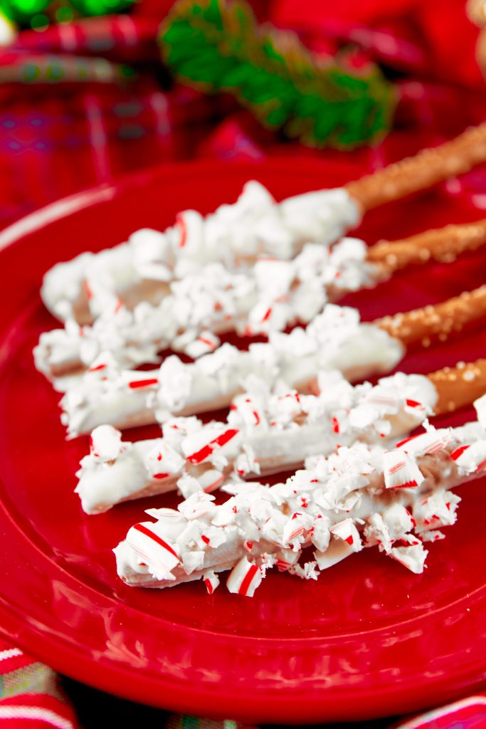 close up on crushed candy canes on christmas pretzel rods on a red plate