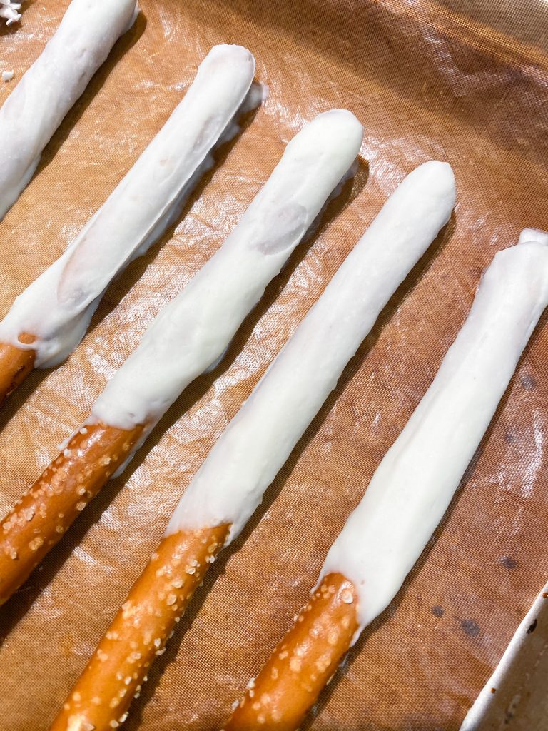 white chocolate setting on pretzel rods on a cookie sheet