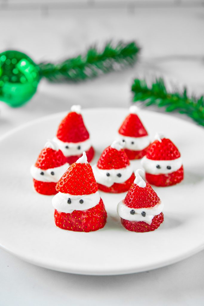 red stuffed Santa strawberries on plate with greenery in the background