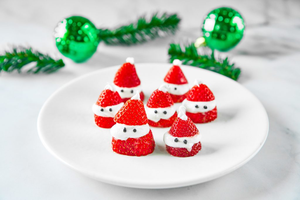 santa strawberries on plate with green ornaments in the background