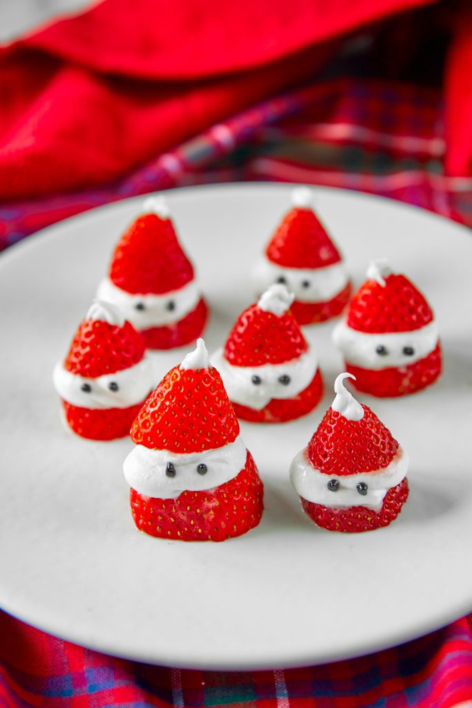 santa strawberries on a white plate on a red tartan background