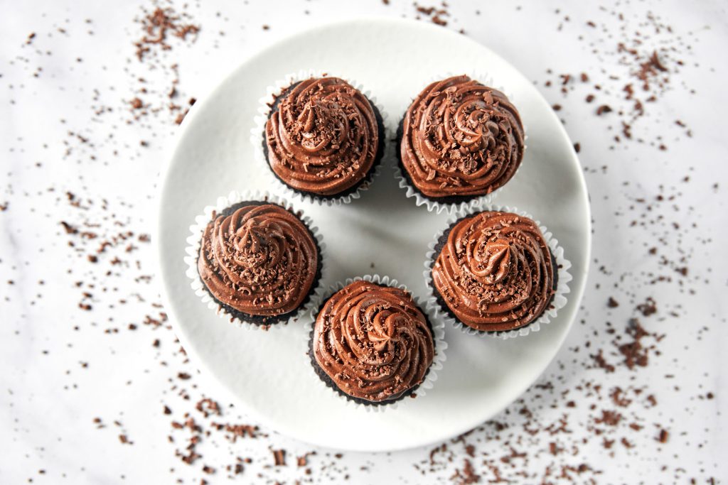 Straight down view of vegan chocolate cupcakes arranged on a white plate.