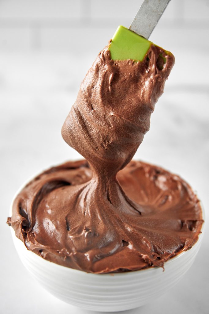 close up of the vegan chocolate frosting in a bowl with a spatula