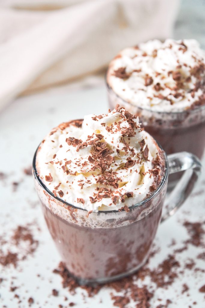 two cups of vegan hot chocolate topped with whipped cream