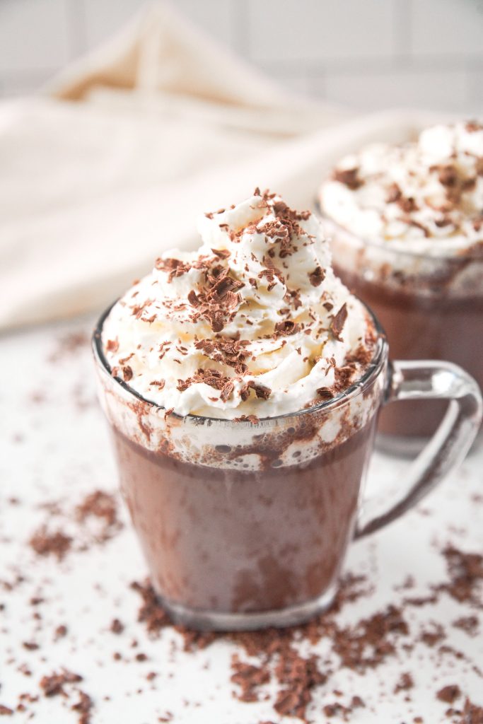 two cups of vegan hot chocolate topped with vegan whipped cream