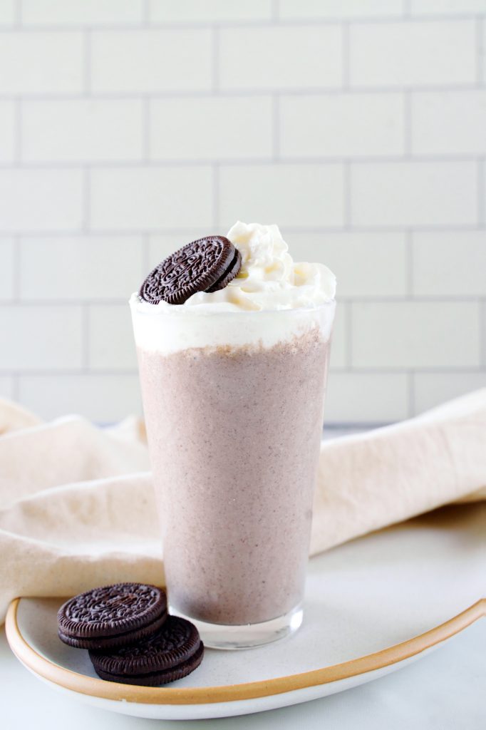 two oreos sitting on a plate with a vegan milkshake