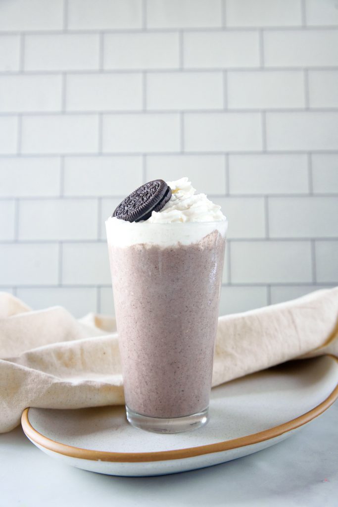 vegan oreo milkshake on a plate with vegan whipped cream