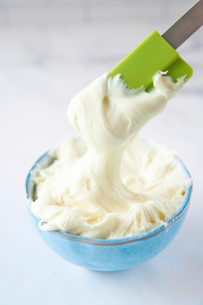 vegan vanilla frosting being scooped out of a bowl