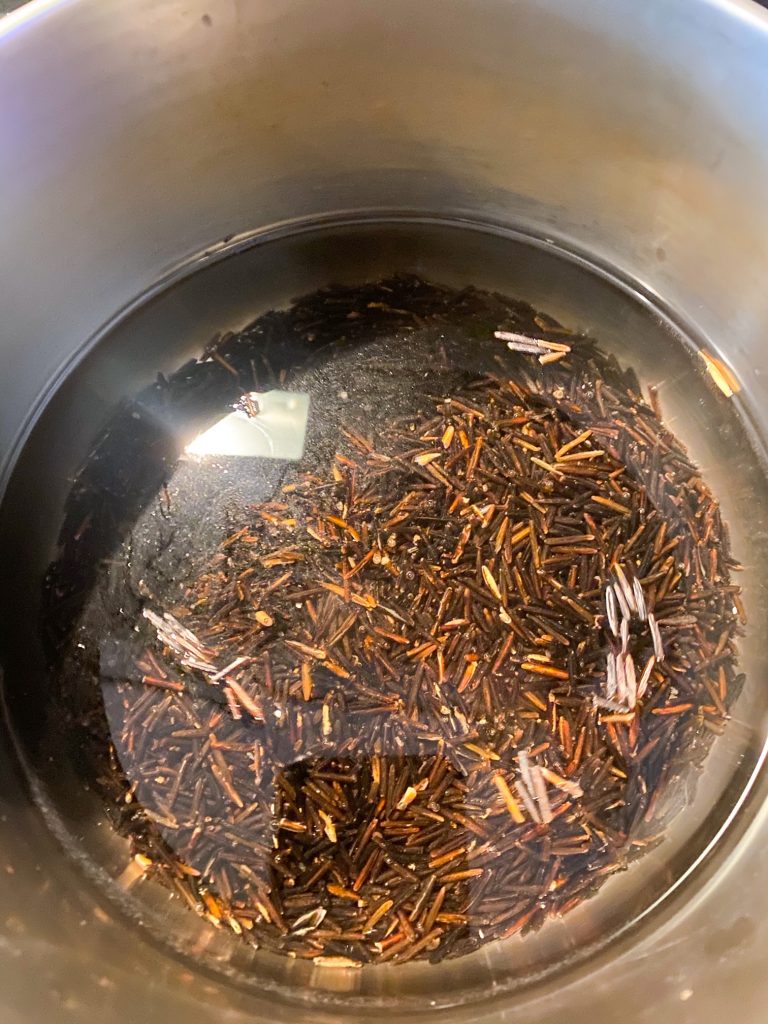 uncooked wild rice in water in a pot on the stove