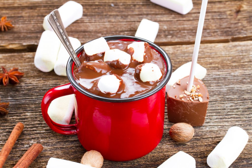 hot chocolate on a stick being used to make hot chocolate in a red cup
