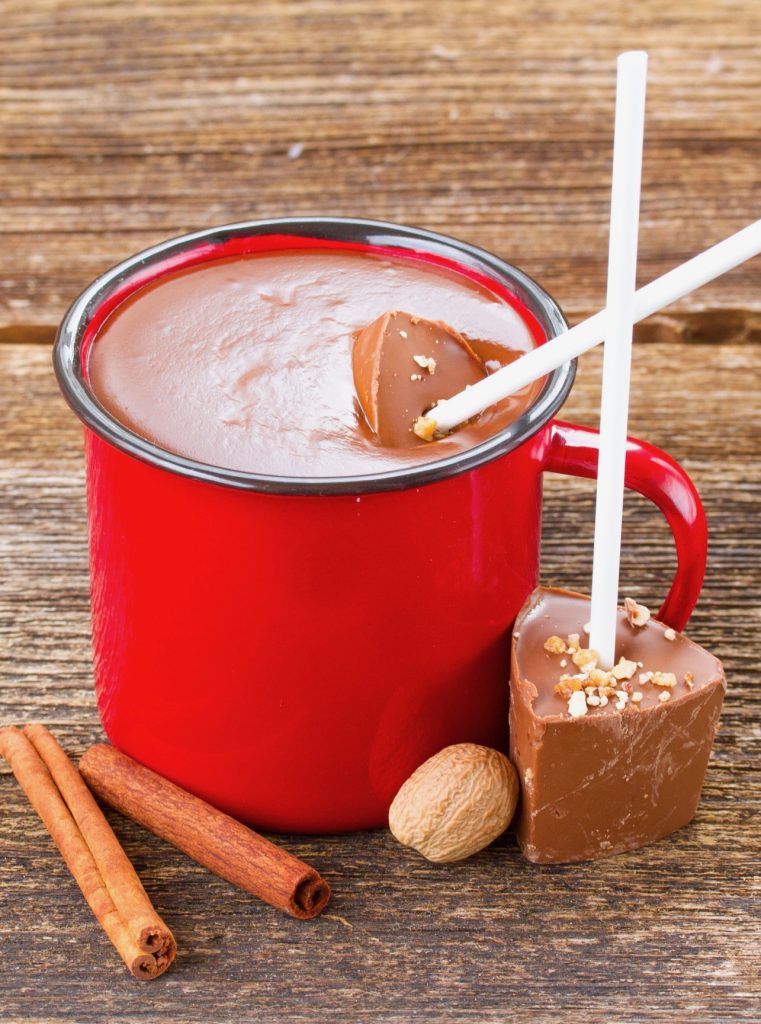hot chocolate sticks being used to make hot chocolate in a red mug
