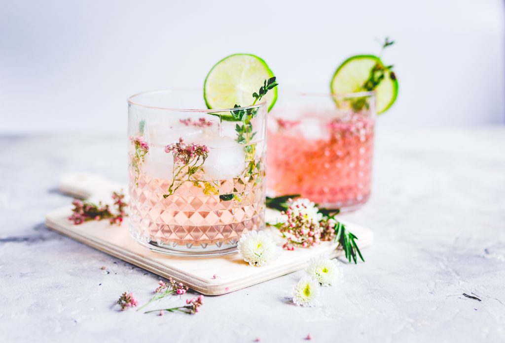 two cups of pink vodka lemonade with flowers for garnish