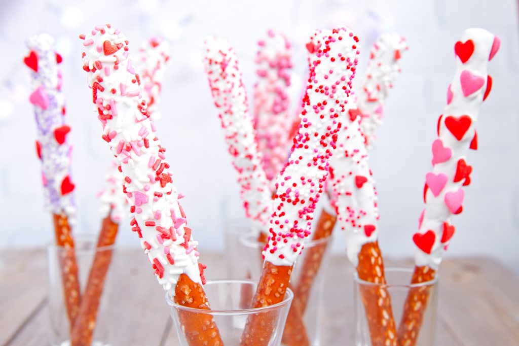 valentines day pretzel rods spread out in cups with heart shaped candy