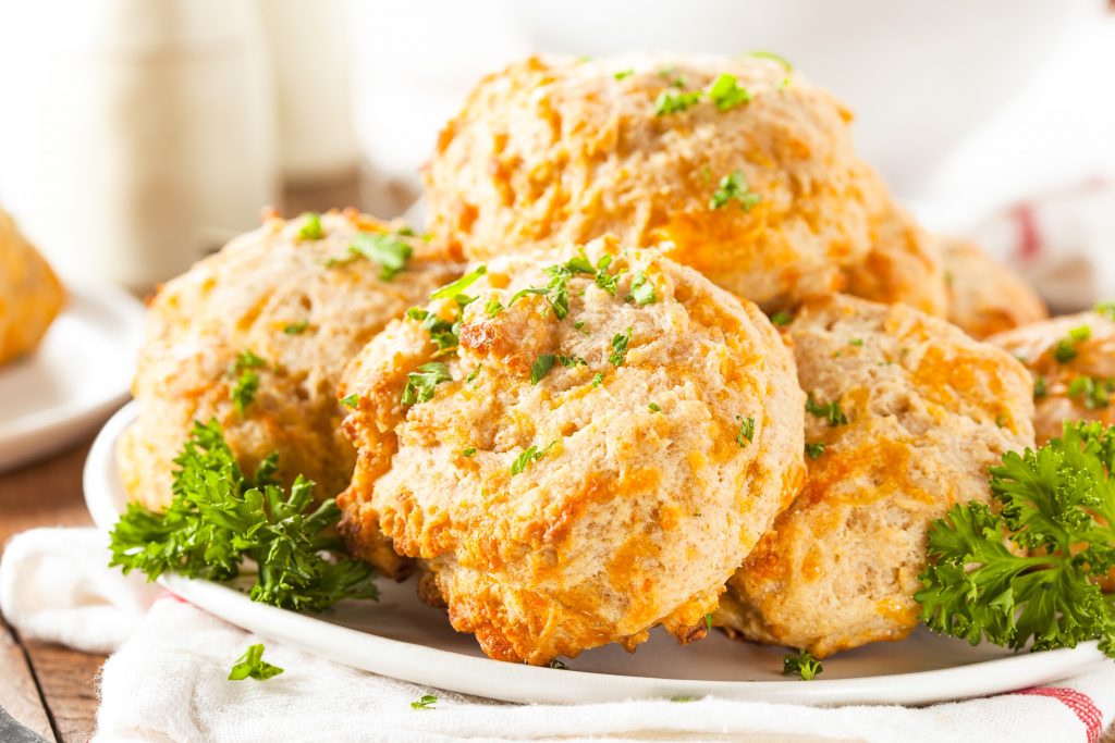 white plate piled high with vegan cheddar biscuits and parsley