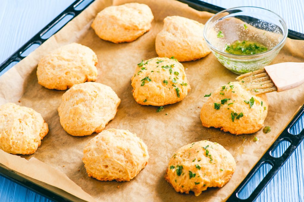 brushing vegan cheddar biscuits with oil and parsley