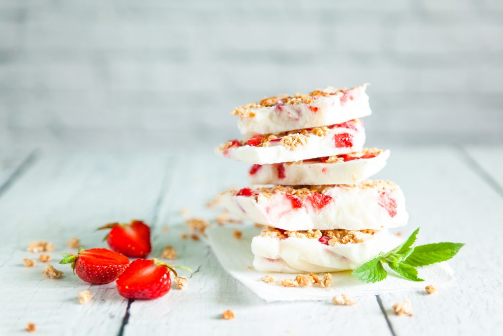 slices of vegan frozen yogurt bark stacked with berries and granola