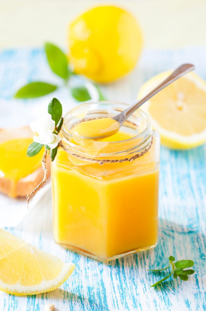 vegan lemon curd in a jar with a blue background