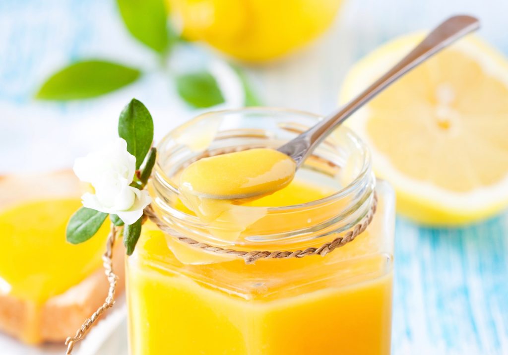 close up of spoon scooping non-dairy lemon curd out of a jar