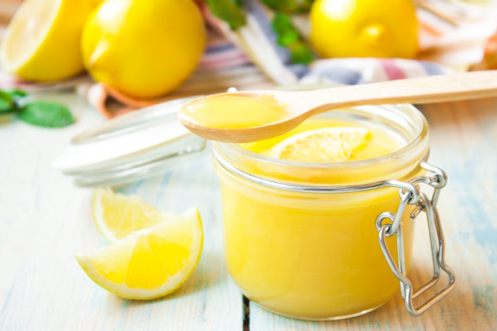vegan lemon curd in a jar with lemons around it