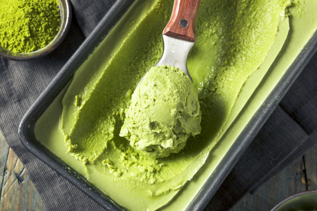 vegan matcha ice cream in a container being scooped out