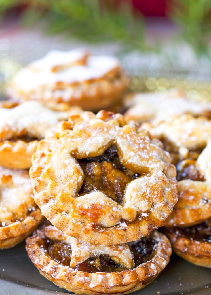 vegan mince pies with little cut outs of star shapes on a plate filled with vegan mincemeat