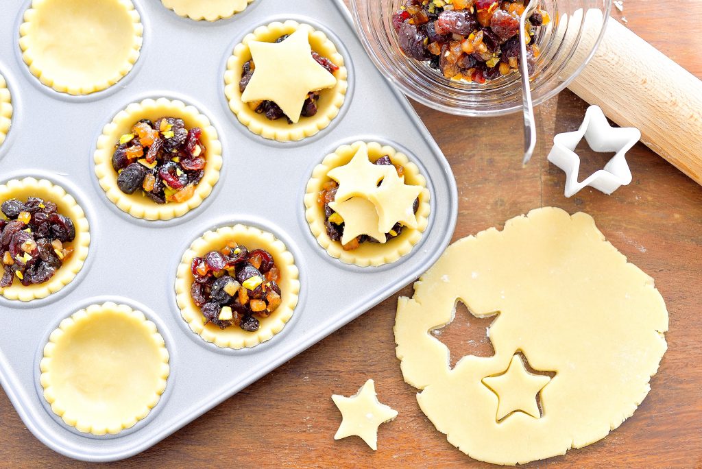 cutting out small squares of vegan mince pies and putting them in a muffin tin