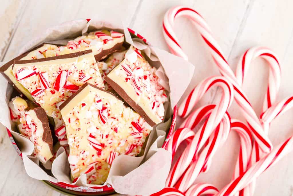 candy canes lying on white background with vegan peppermint bark in a baking tin