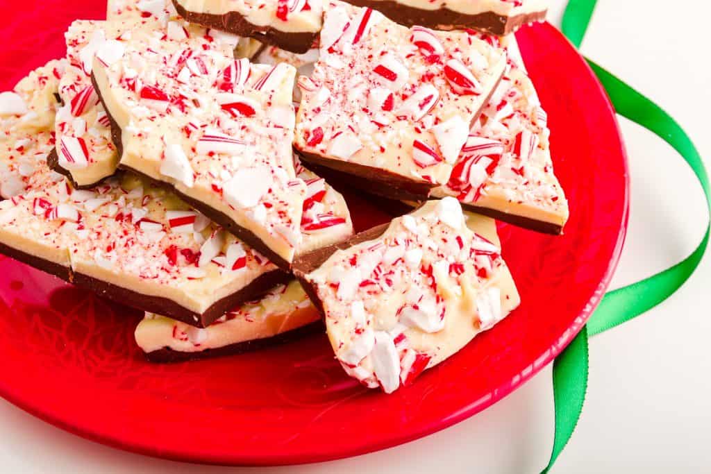 homemade peppermint bark on a red plate with a green ribbon