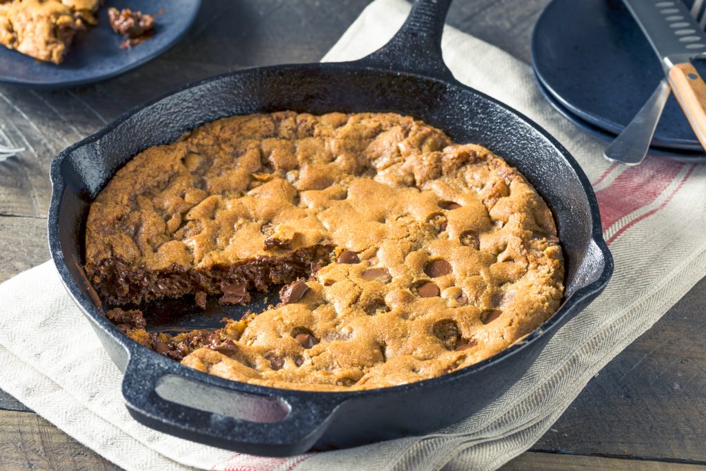 vegan skillet cookie with a slice cut out of it being served