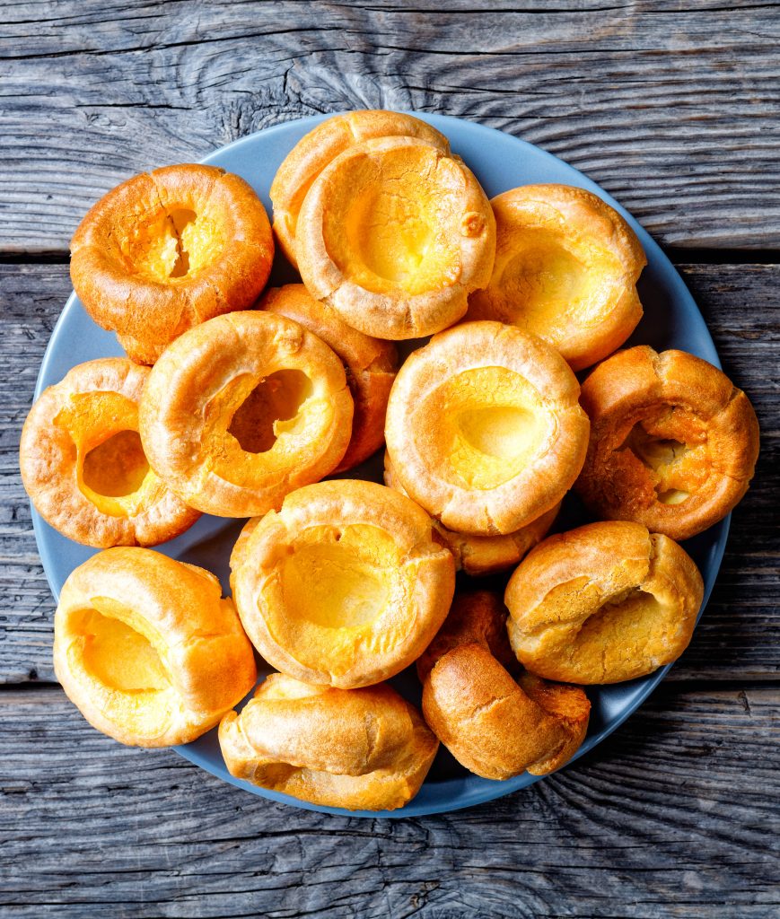 blue plate filled with vegan yorkshire puddings on a grey background
