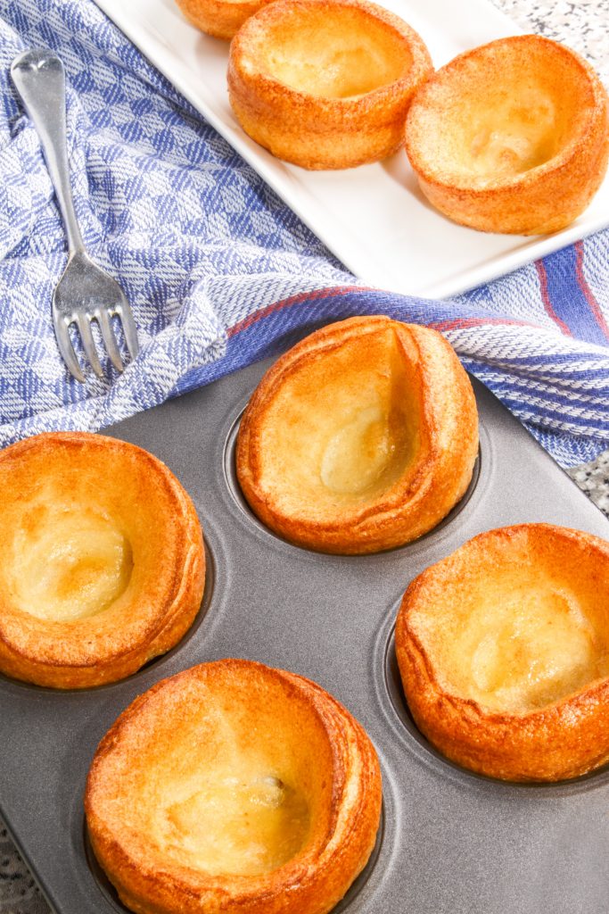 vegan yorkshire puddings being made in a cup with blue towel and fork around them 