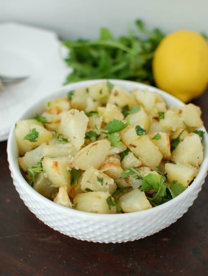 Photo of Lemon Cilantro Potatoes being served in a textured white bowl.