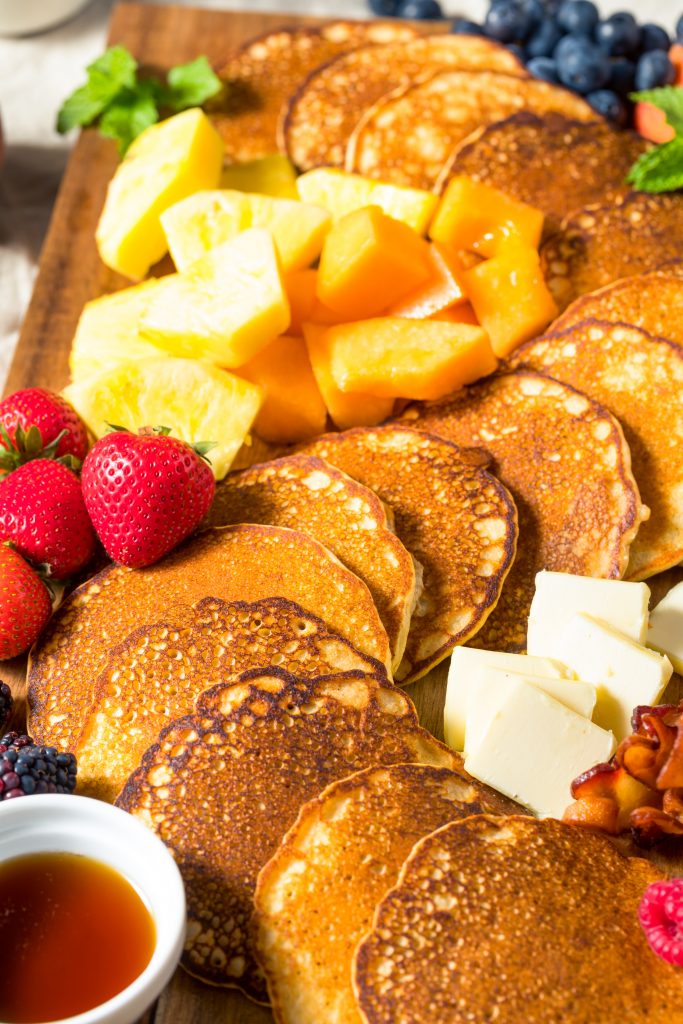close up of pancakes on a breakfast board with fruit