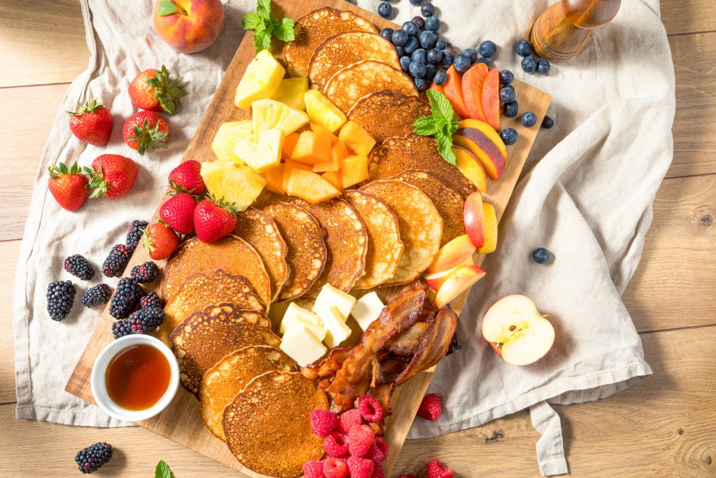 overhead image of a breakfast charcuterie board with pancakes, fruit and more