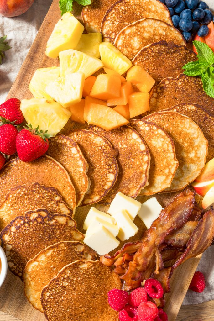 pancakes and fruits arranged on a breakfast charcuterie board