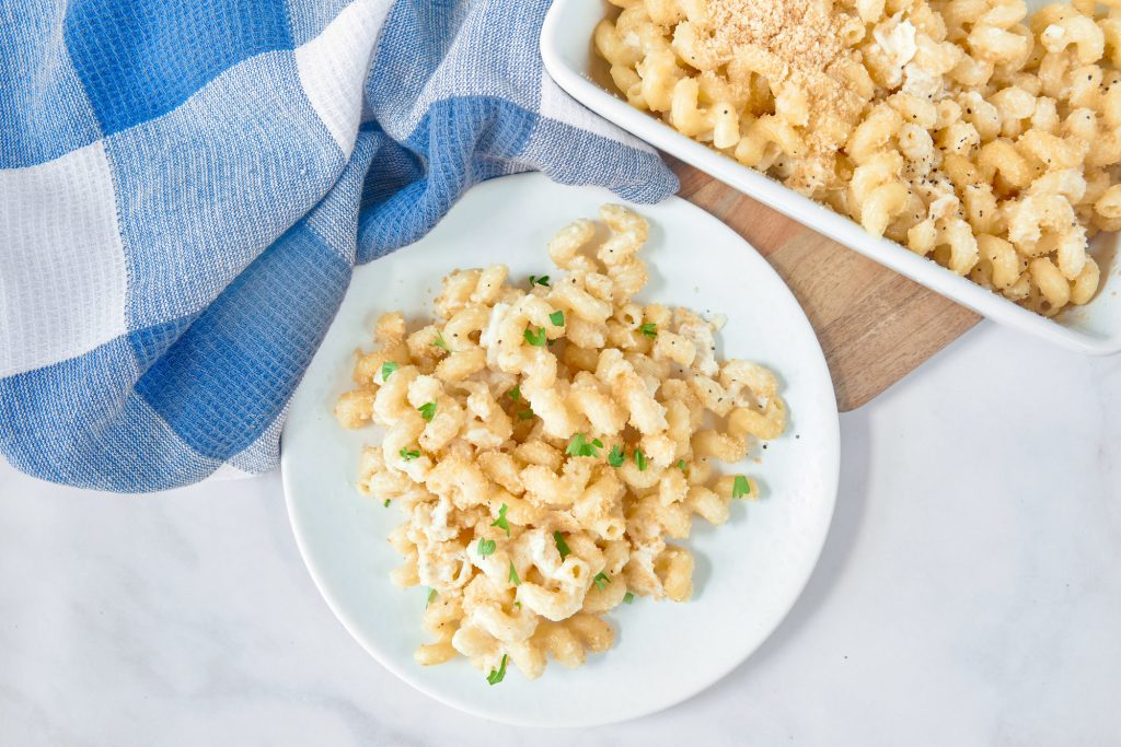 Baked brie mac and cheese from above on a plate with a cutting board, blue and white towel, and baking dish