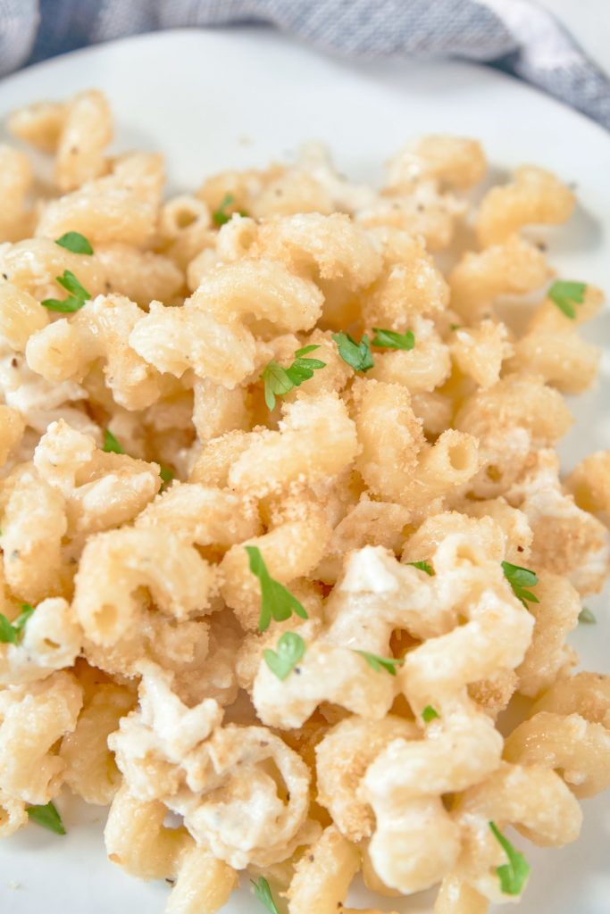 A close up of brie mac and cheese with spiraled noodles parsley and breadcrumbs.