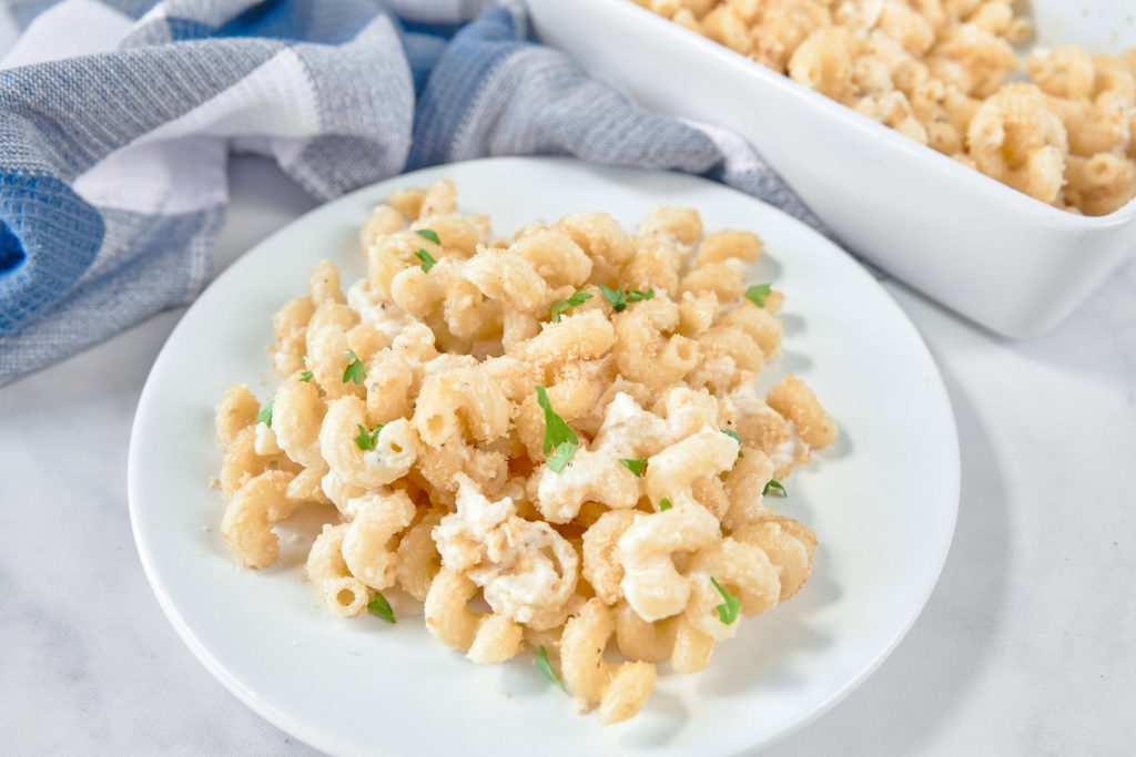 brie mac and cheese on a white plate with baking dish in the background