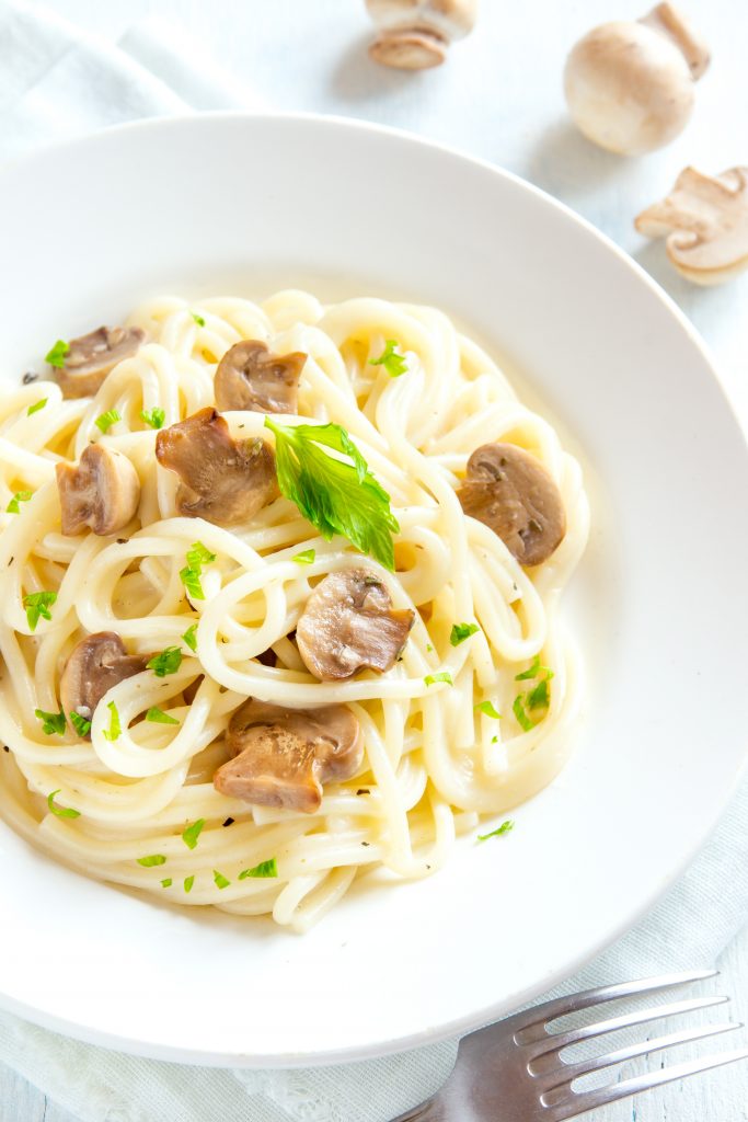 dish of creamy mushroom pasta on the side with a fork
